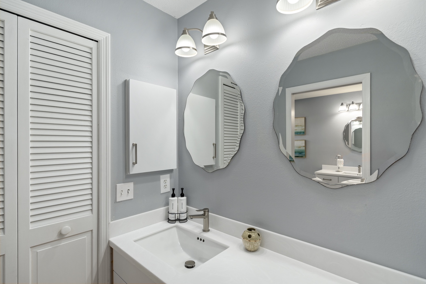 Freshen up in your serene bathroom with elegant scalloped mirrors and soft coastal touches that make every morning feel like a retreat.