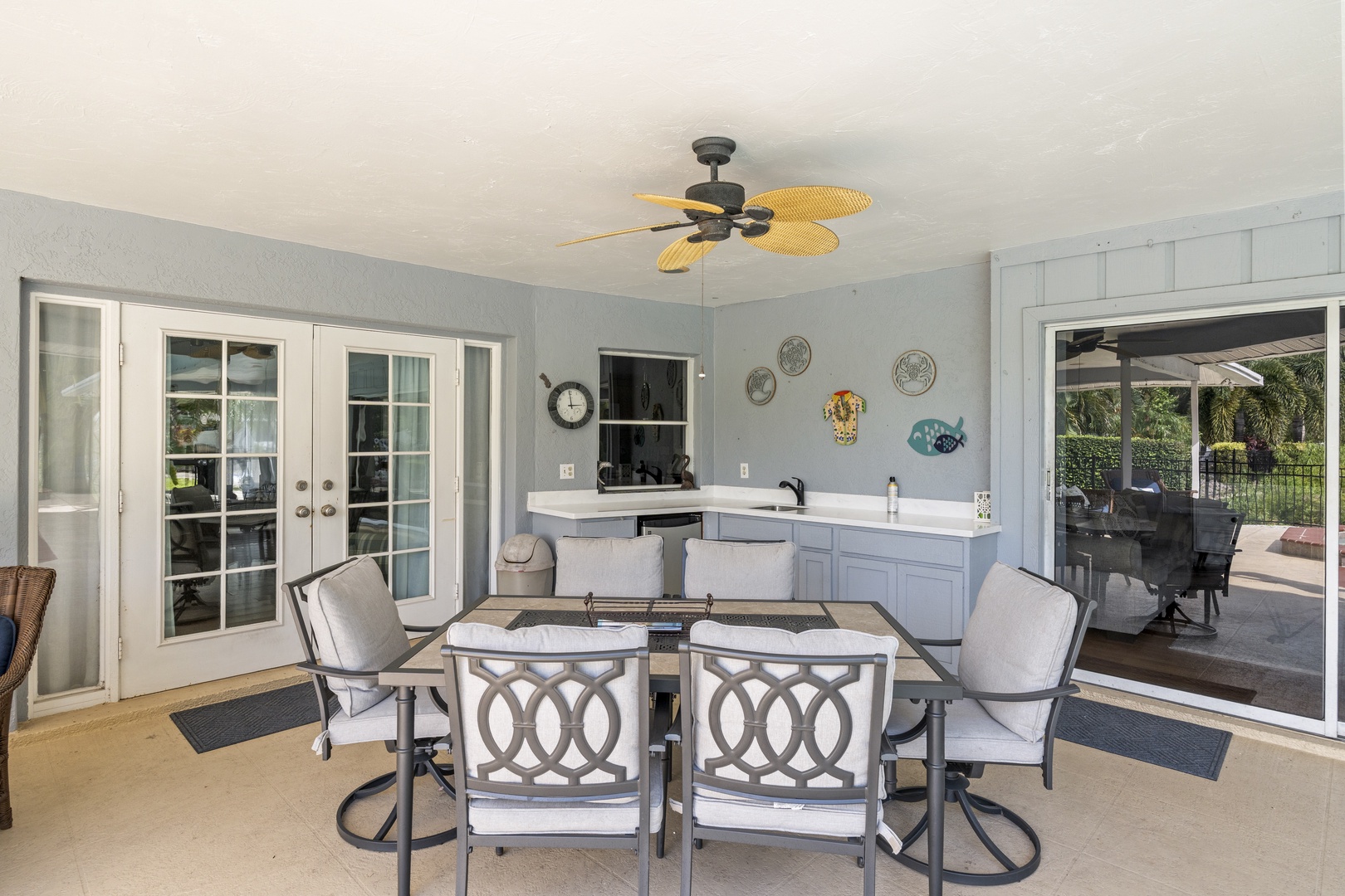 A covered patio space ideal for al fresco dining, featuring a full outdoor kitchen and charming coastal accents. Your ceiling fan keeps you comfortable while you dine and unwind.