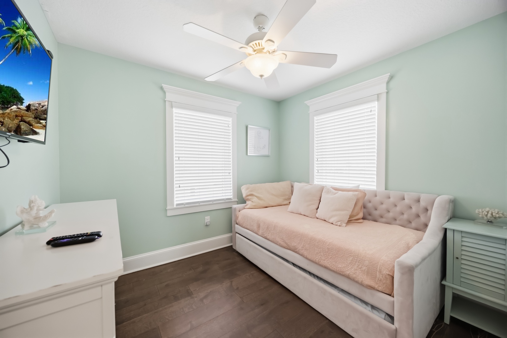 Relax in your serene coastal retreat with soothing mint walls, plush seating, and tropical artwork that sets the perfect vacation mood.