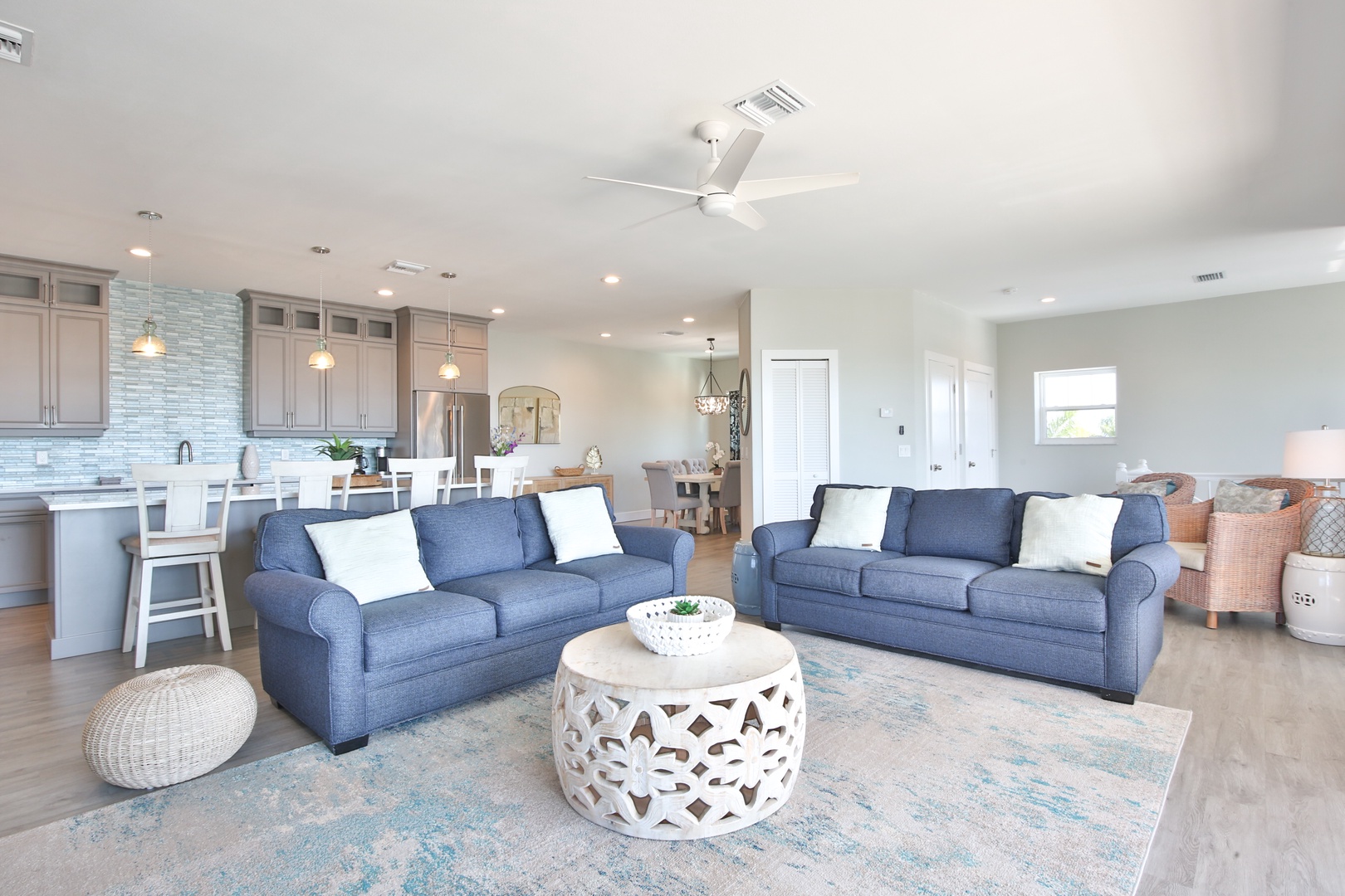 Sink into plush blue sofas in your open-concept living space, where coastal elegance meets modern comfort for perfect relaxation.
