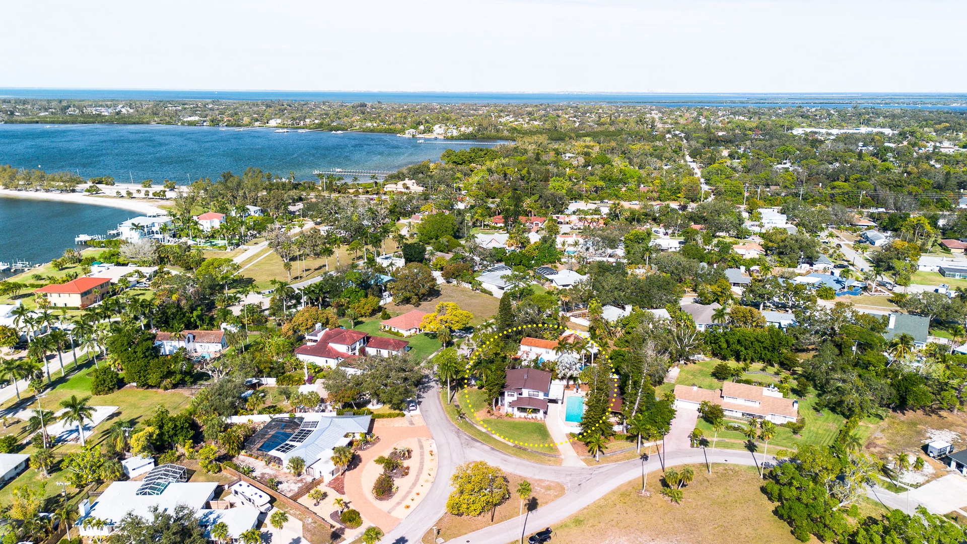 Aerial view of a waterfront residential neighborhood with tree-lined streets and coastal access nearby.