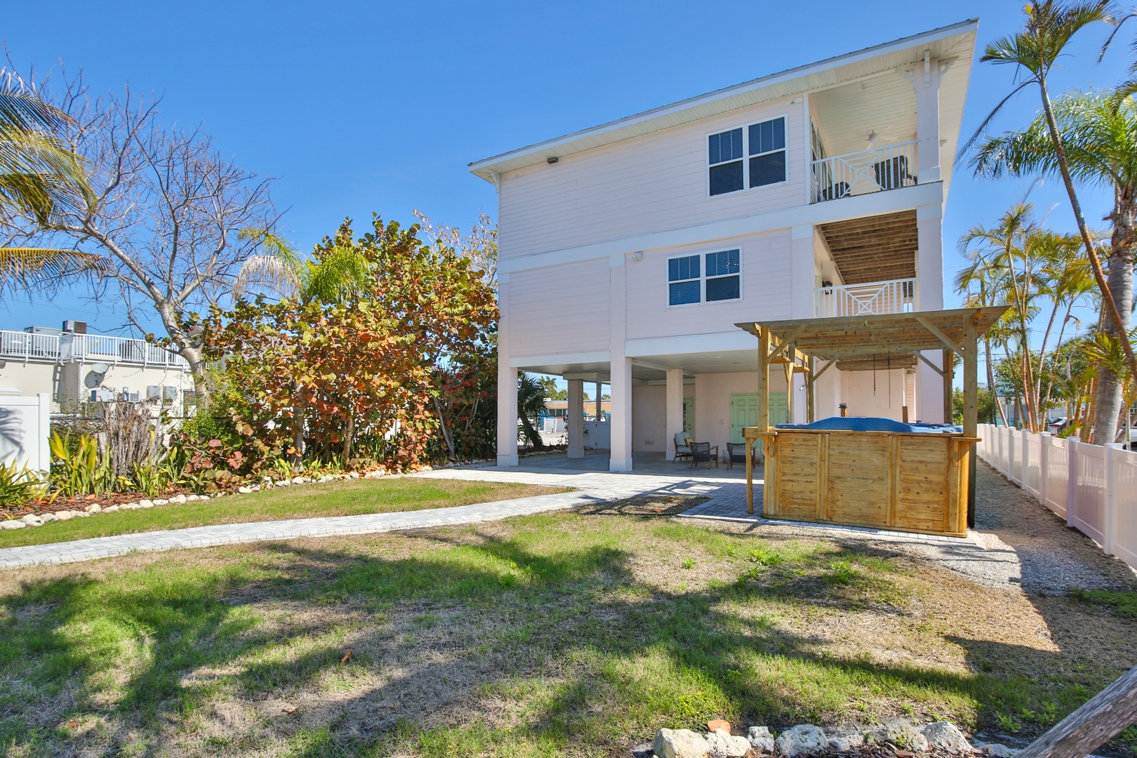 Modern coastal home with elevated design and tropical landscaping in a peaceful neighborhood setting.
