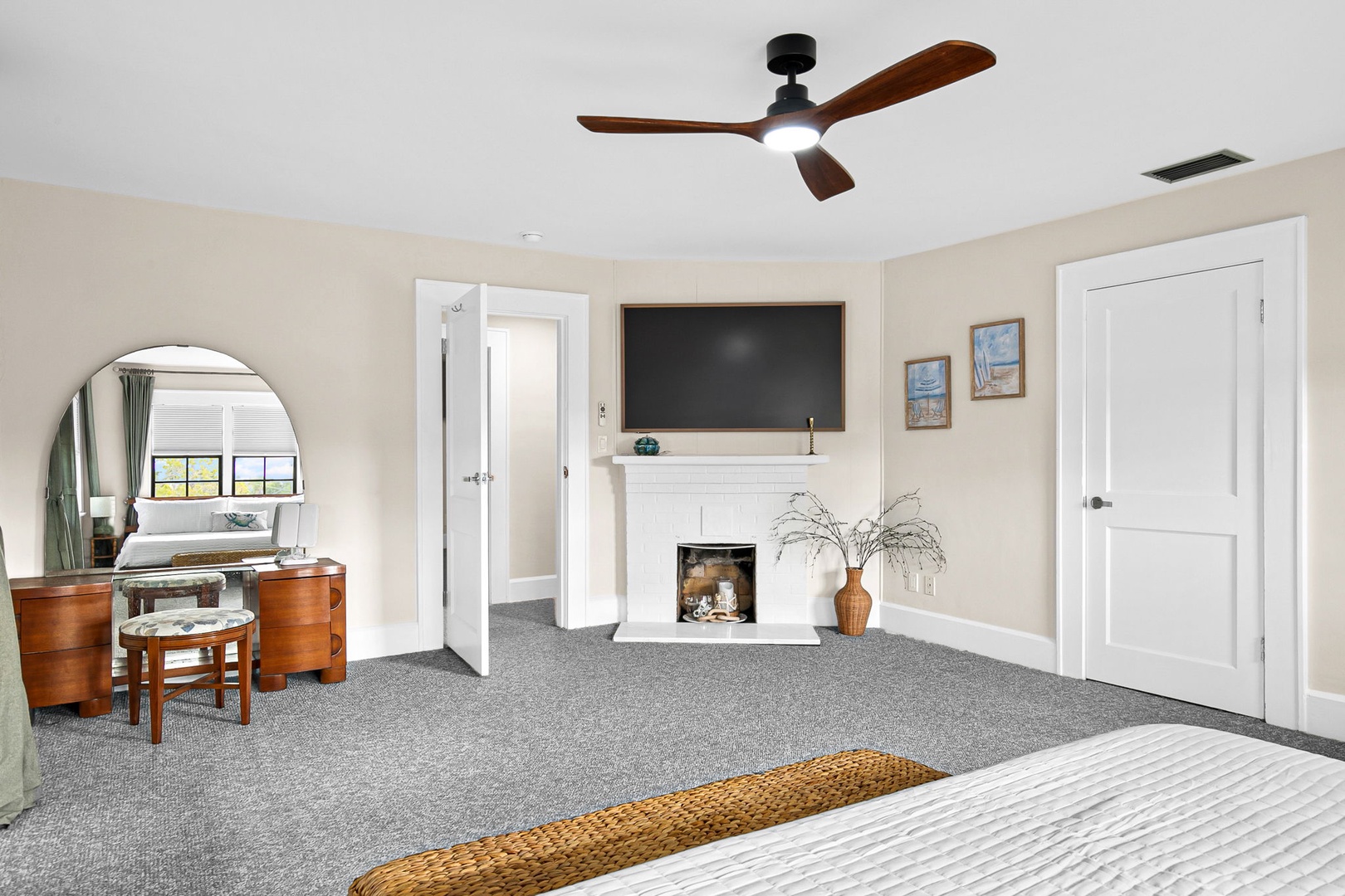 Unwind in your spacious bedroom featuring a cozy fireplace, elegant vanity area, and mounted TV for ultimate relaxation.