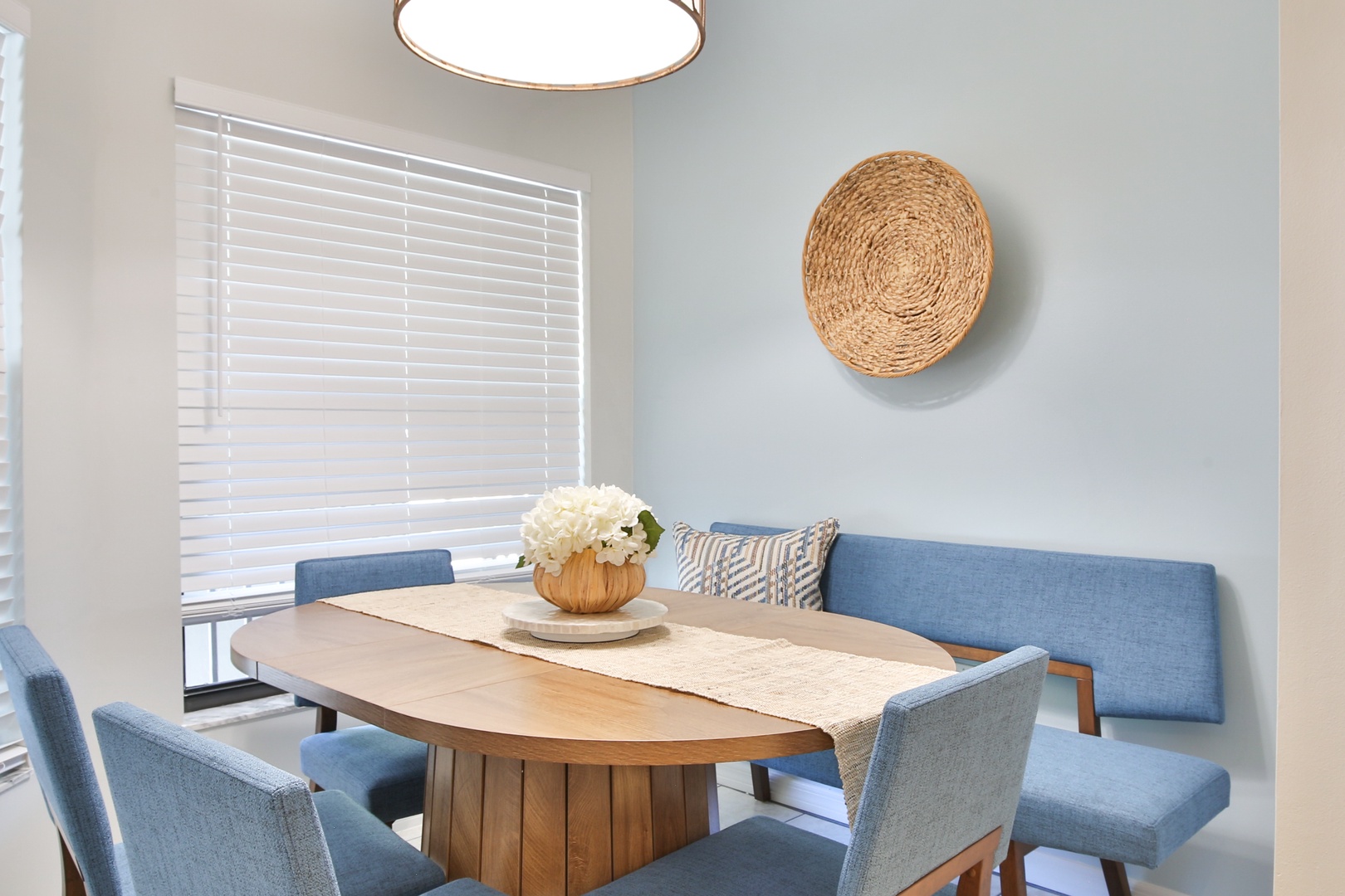 Gather around this inviting dining nook where soft blue seating and warm wood create the perfect spot for morning coffee or evening meals together.