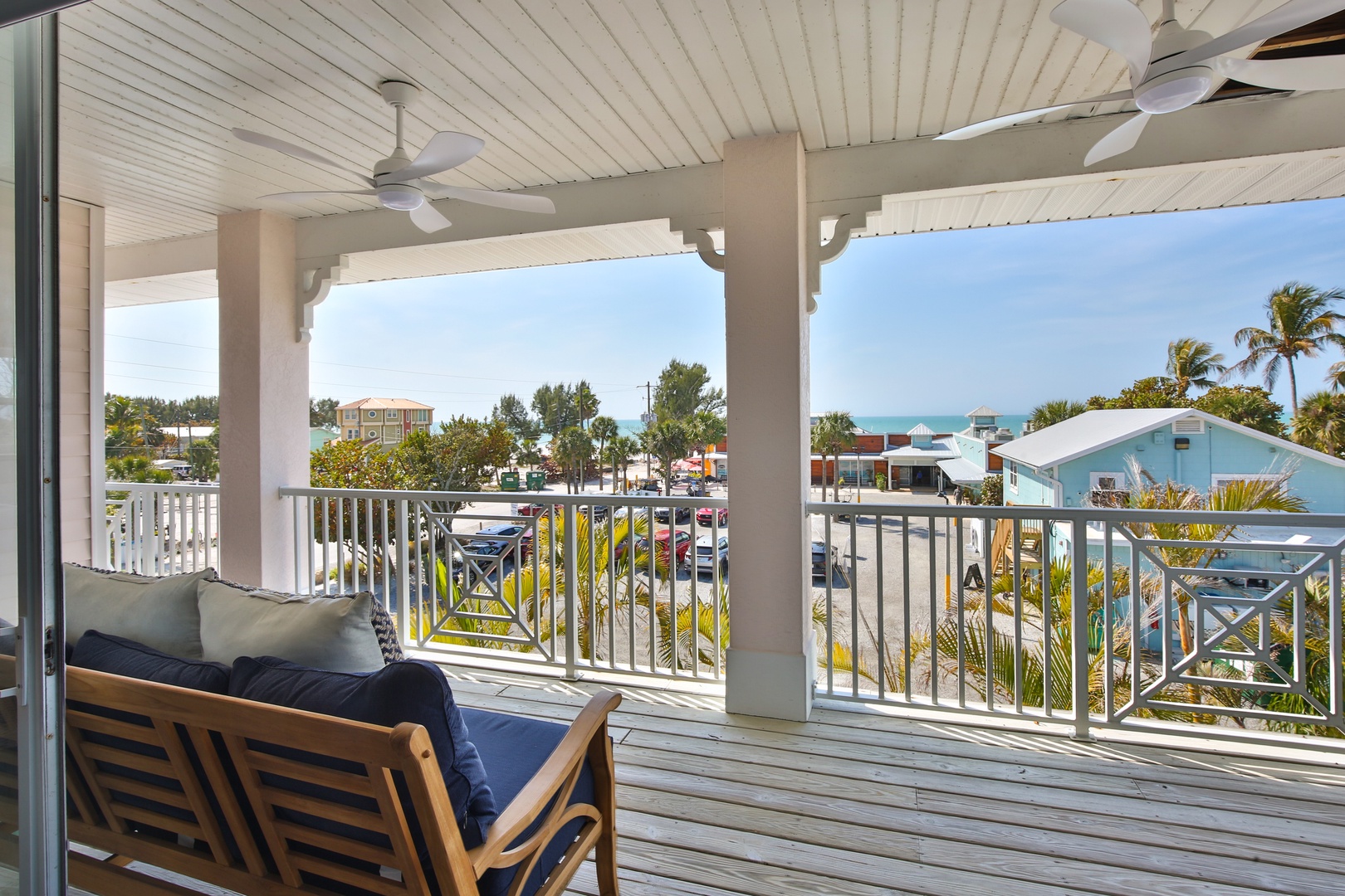 Relax on your private covered balcony with comfortable seating and ceiling fans, overlooking tropical surroundings and colorful island homes.