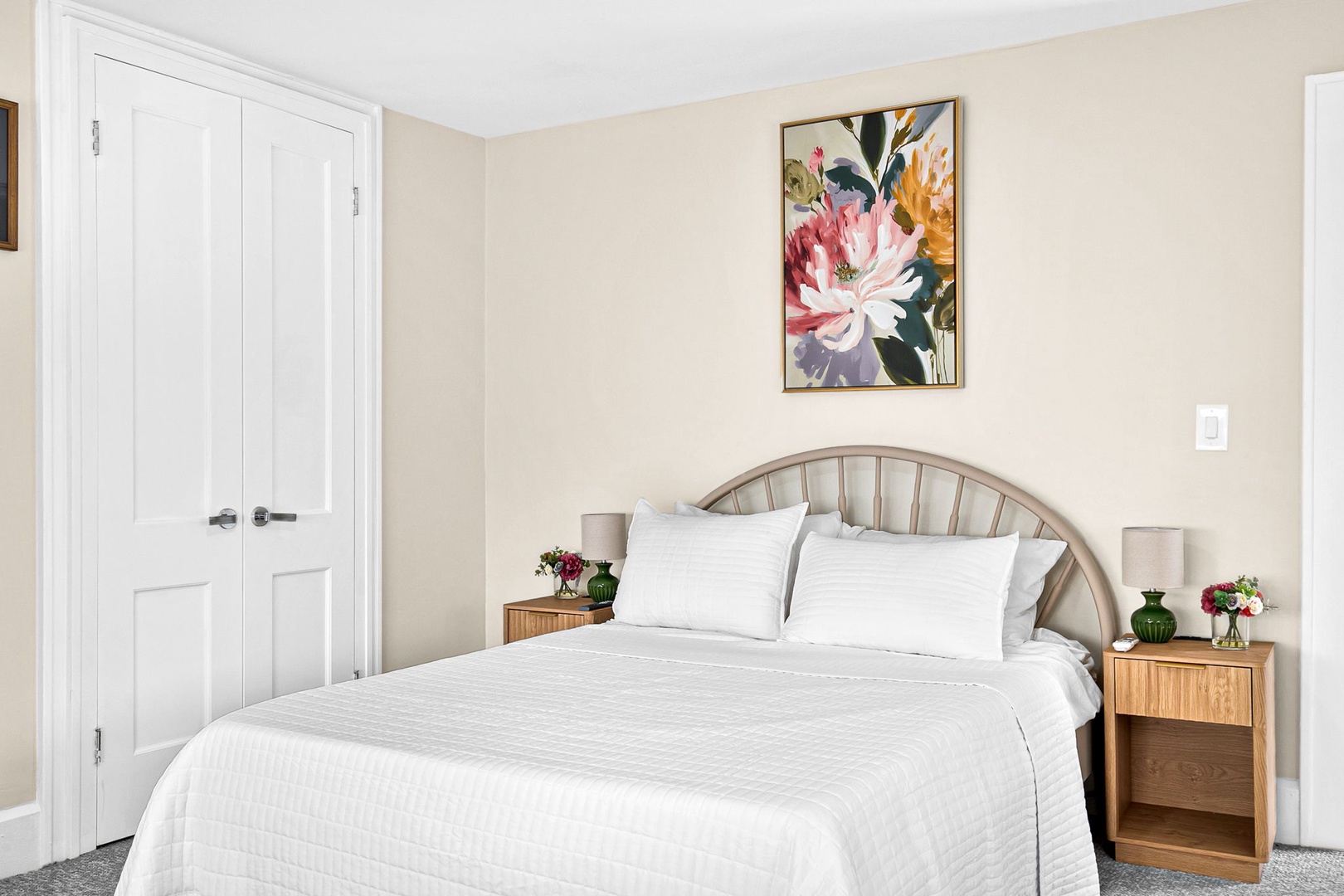 You'll love drifting off to sleep in this serene bedroom, with its plush bedding and vibrant floral artwork creating a peaceful retreat.