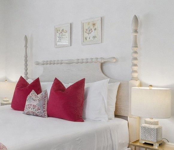 Your elegant bedroom features crisp white linens accented with vibrant red pillows, creating a perfect blend of comfort and style.