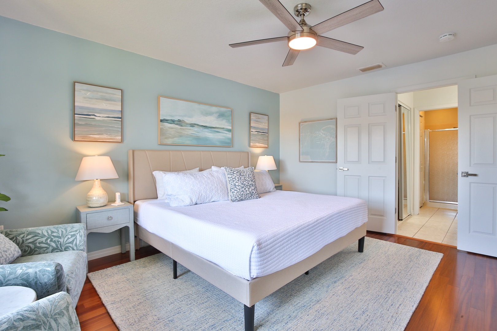 Drift off in your coastal-inspired sanctuary where soft sea-foam walls and ocean artwork create perfect tranquility beneath the gentle ceiling fan breeze.