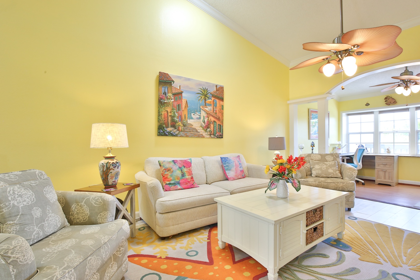 Picture yourself unwinding in this cheerful living room, where sunny yellow walls and coastal charm welcome you. Sink into plush sofas, enjoy tropical ceiling fans, and let vibrant artwork inspire your vacation mood.