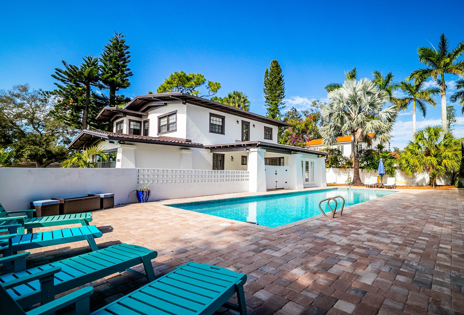 A stunning tropical villa with pristine pool surrounded by lush palm trees under brilliant blue skies - your private paradise awaits.