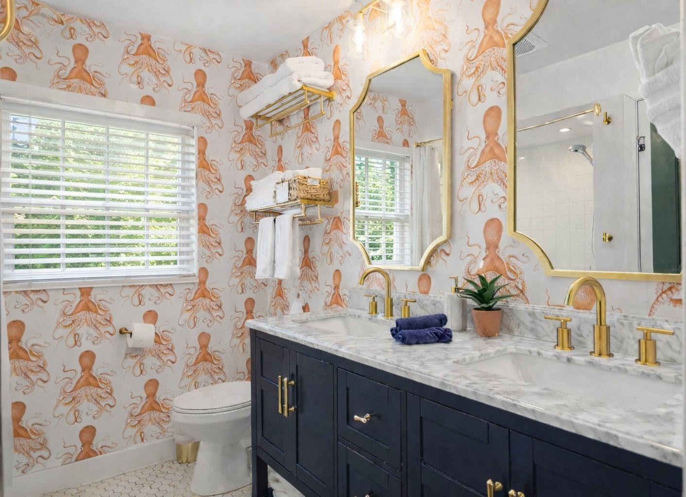 Step into your whimsical bathroom featuring playful octopus wallpaper, elegant marble counters, and brass fixtures that create a perfect coastal retreat.