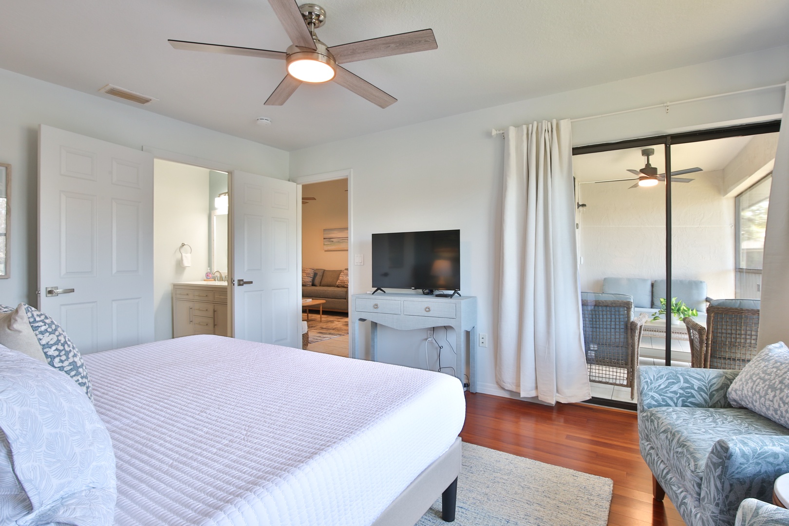 Relax in your serene bedroom featuring a ceiling fan, flat-screen TV, and private patio access for peaceful morning coffee.