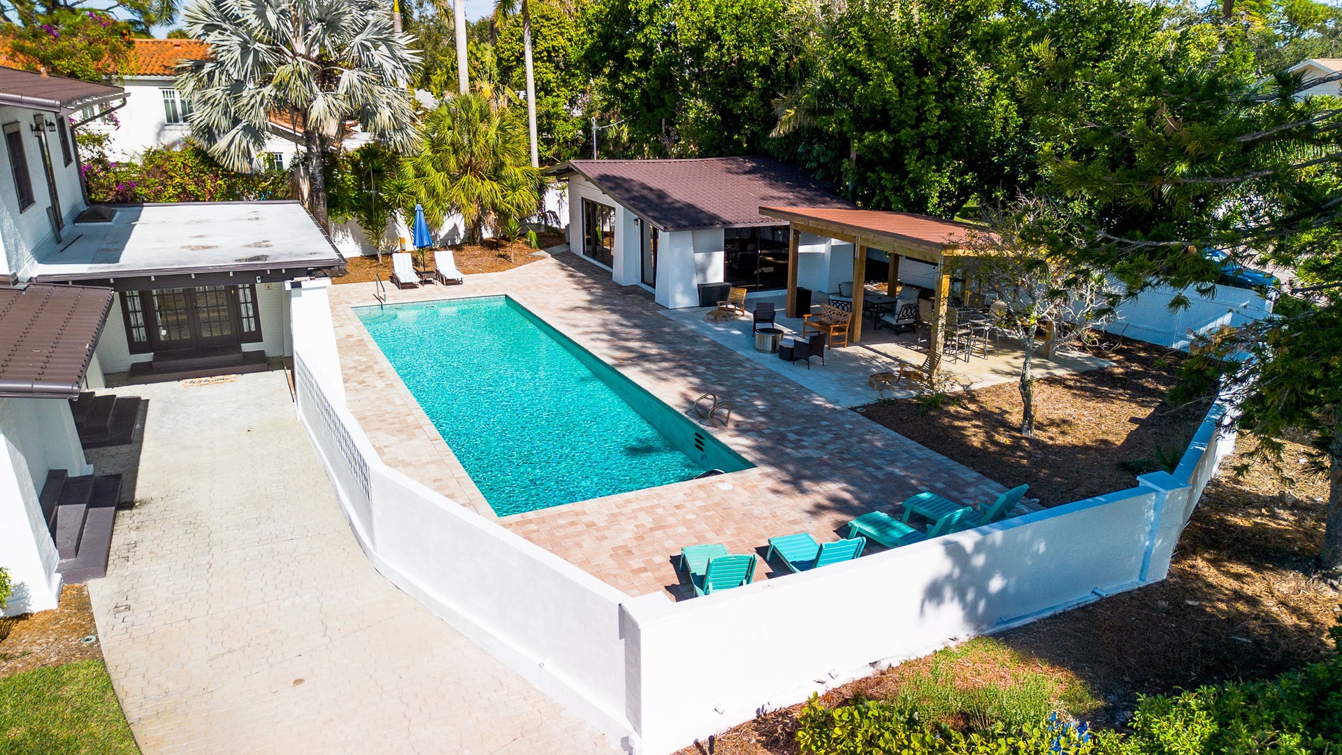 Aerial view of a beautiful vacation rental property featuring a sparkling swimming pool surrounded by tropical landscaping and mature trees.