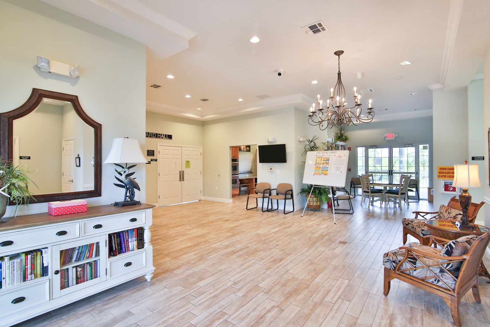 Spacious communal lounge with warm wood-look floors, elegant chandelier, and cozy seating areas—perfect for relaxing with a book, planning your day, or mingling with fellow travelers.