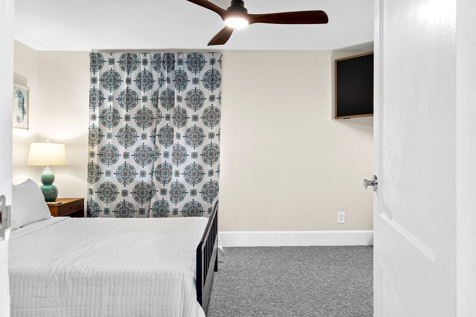Rest peacefully in your spacious bedroom featuring elegant wallpaper and modern comforts like a ceiling fan and flat-screen TV.