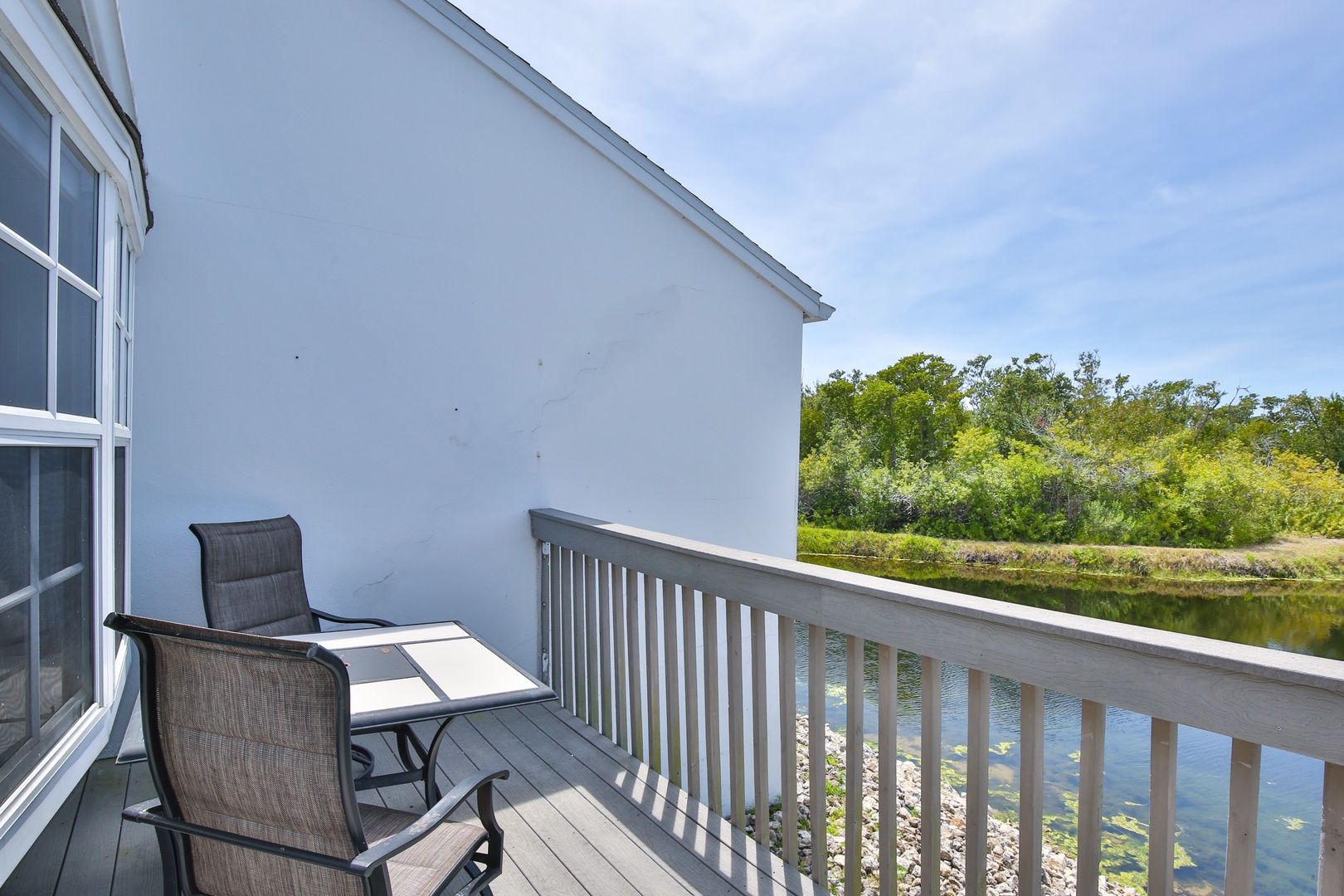 The balcony overlooks tranquil waterfront views framed by lush greenery, offering a peaceful spot to unwind with your morning coffee or watch the reflections dance on the water.