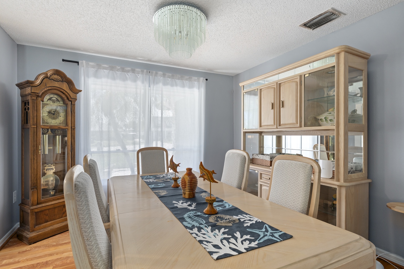 Gather around this elegant dining table for shared meals and conversations. Natural light filters through sheer curtains, casting a soft glow over your dining experience.