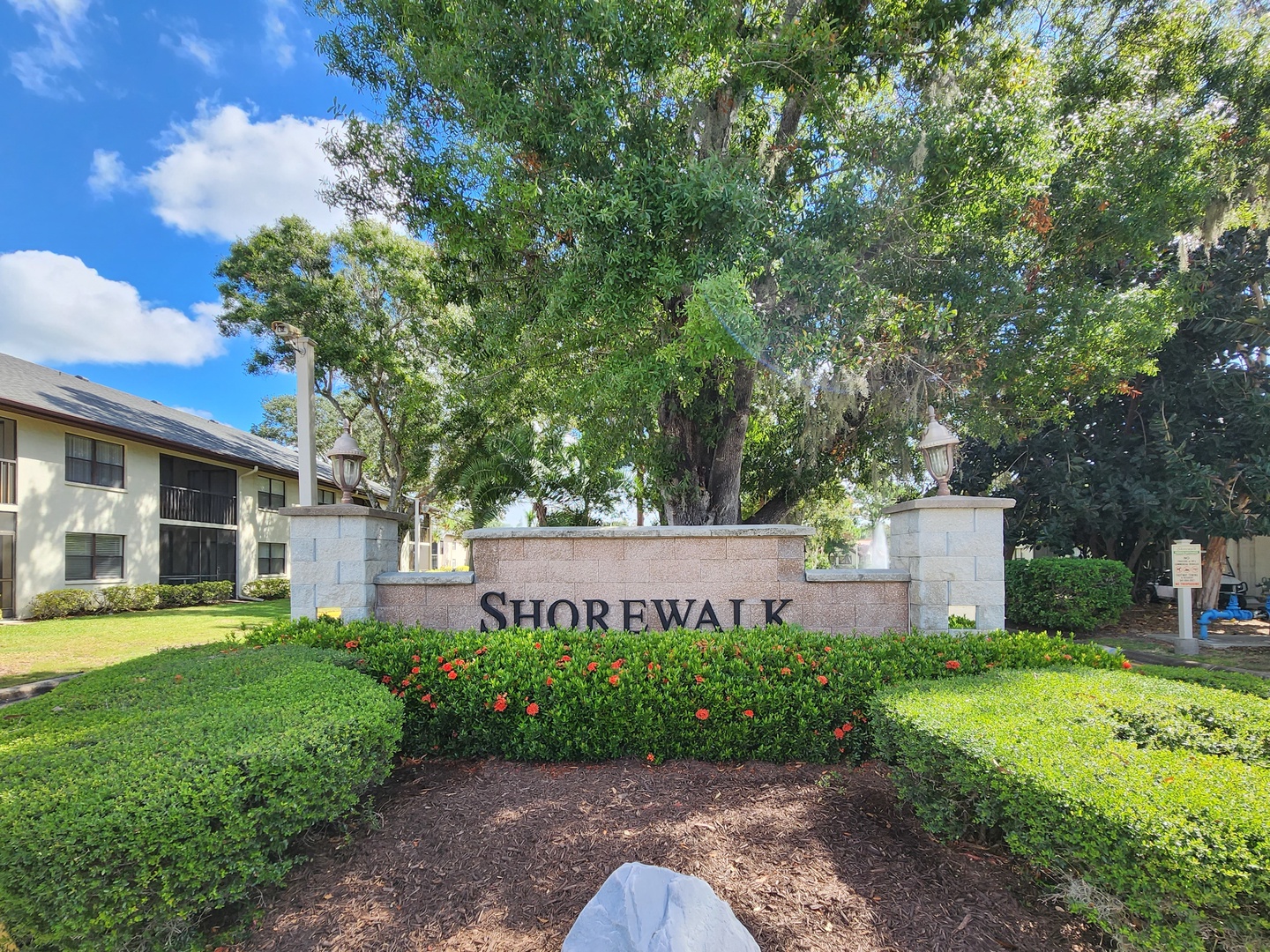 Welcome to Shorewalk, a beautifully landscaped community entrance surrounded by mature trees and manicured gardens.