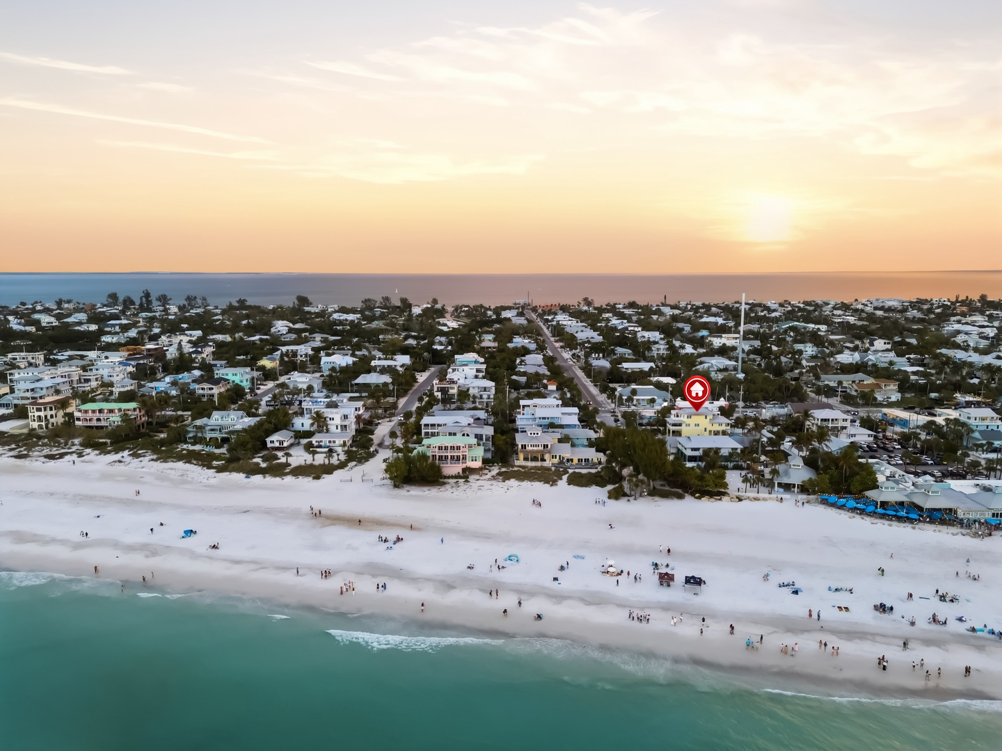 Stunning aerial perspective of a beautiful beachfront community at sunset, showcasing pristine white sand beaches and turquoise waters.
