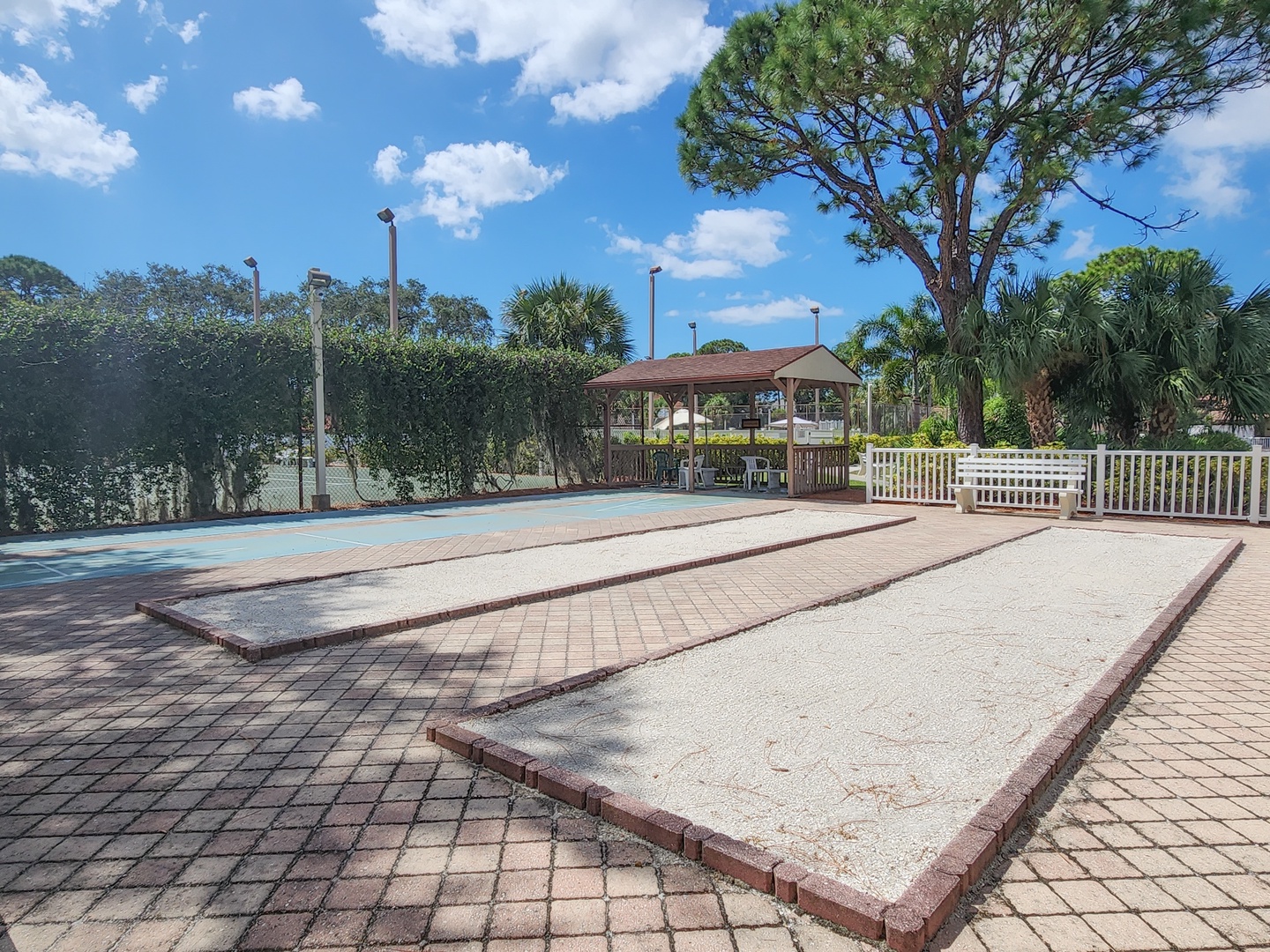 Spacious outdoor recreation area featuring multiple courts surrounded by tropical landscaping and covered pavilion for relaxation.