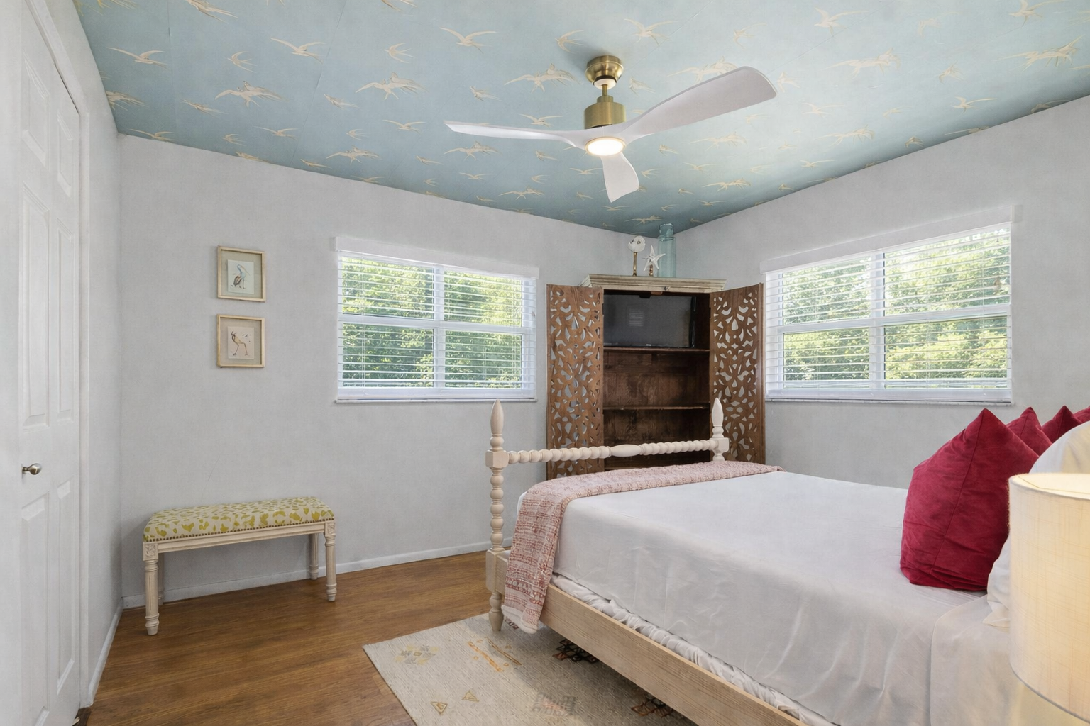 Your peaceful bedroom features whimsical crane-patterned ceiling, crisp linens, and bright windows overlooking lush greenery for restful mornings.