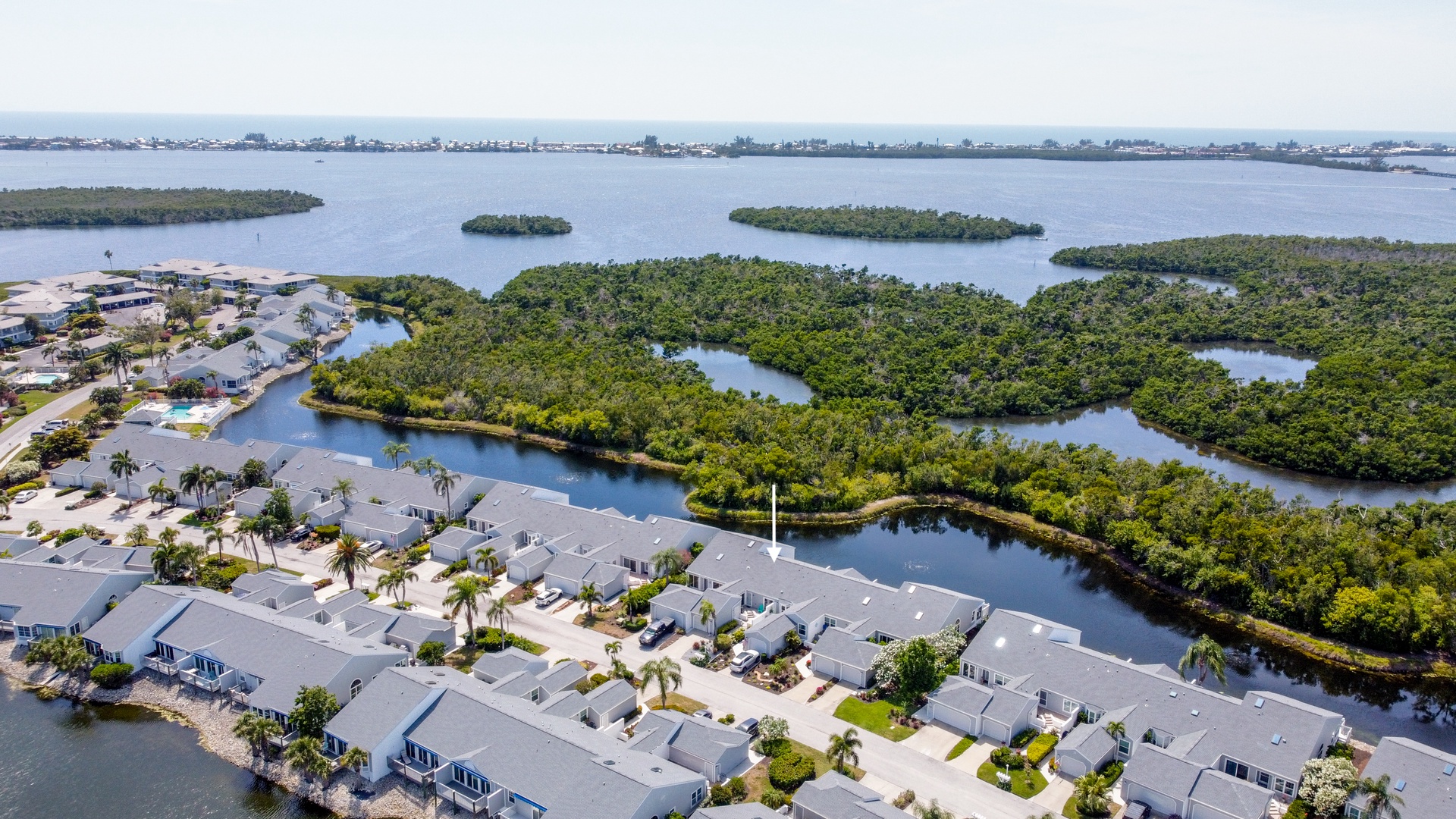 Aerial view of the waterfront property community nestled among lush mangrove islands, with peaceful bay waters and coastal scenery visible in all directions.