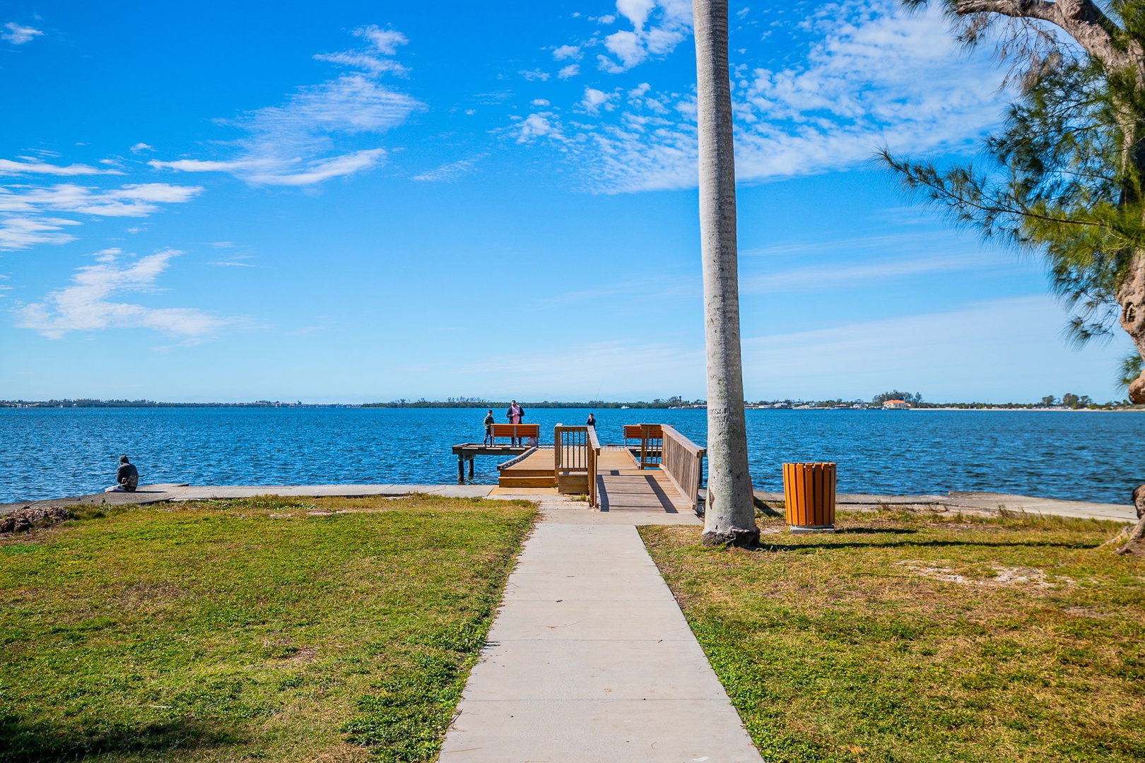 Waterfront property features a private dock extending into crystal-clear waters, surrounded by tropical palms and manicured grounds.