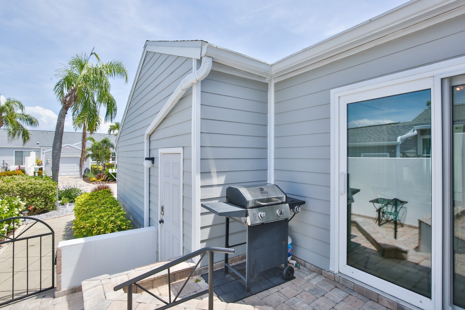 Your private patio features a gas grill ready for outdoor cooking, surrounded by tropical landscaping and palm trees for a true vacation retreat atmosphere.