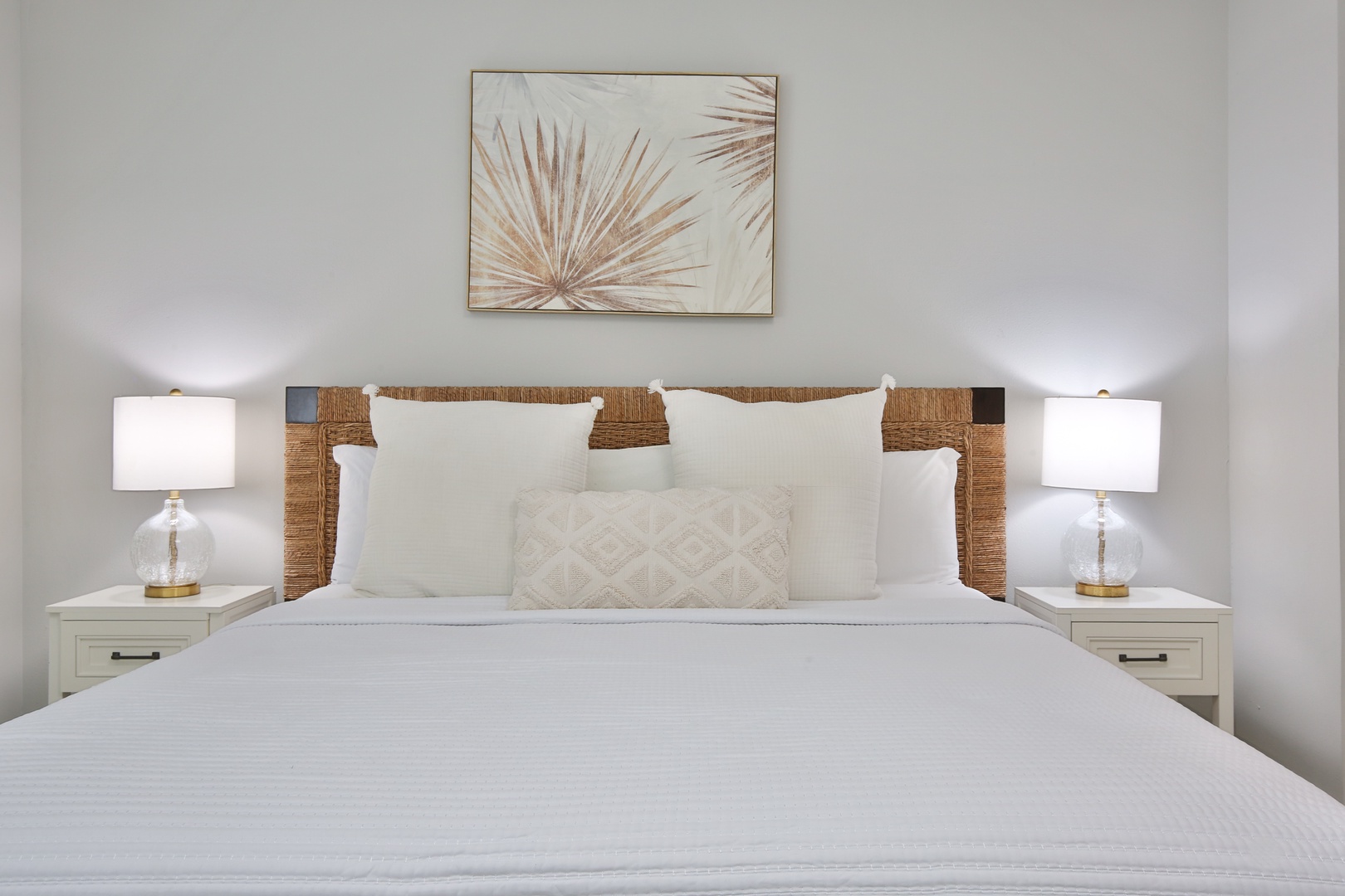 Sink into crisp white linens and plush pillows in this serene bedroom, where warm bedside lighting creates the perfect ambiance for your restful retreat.