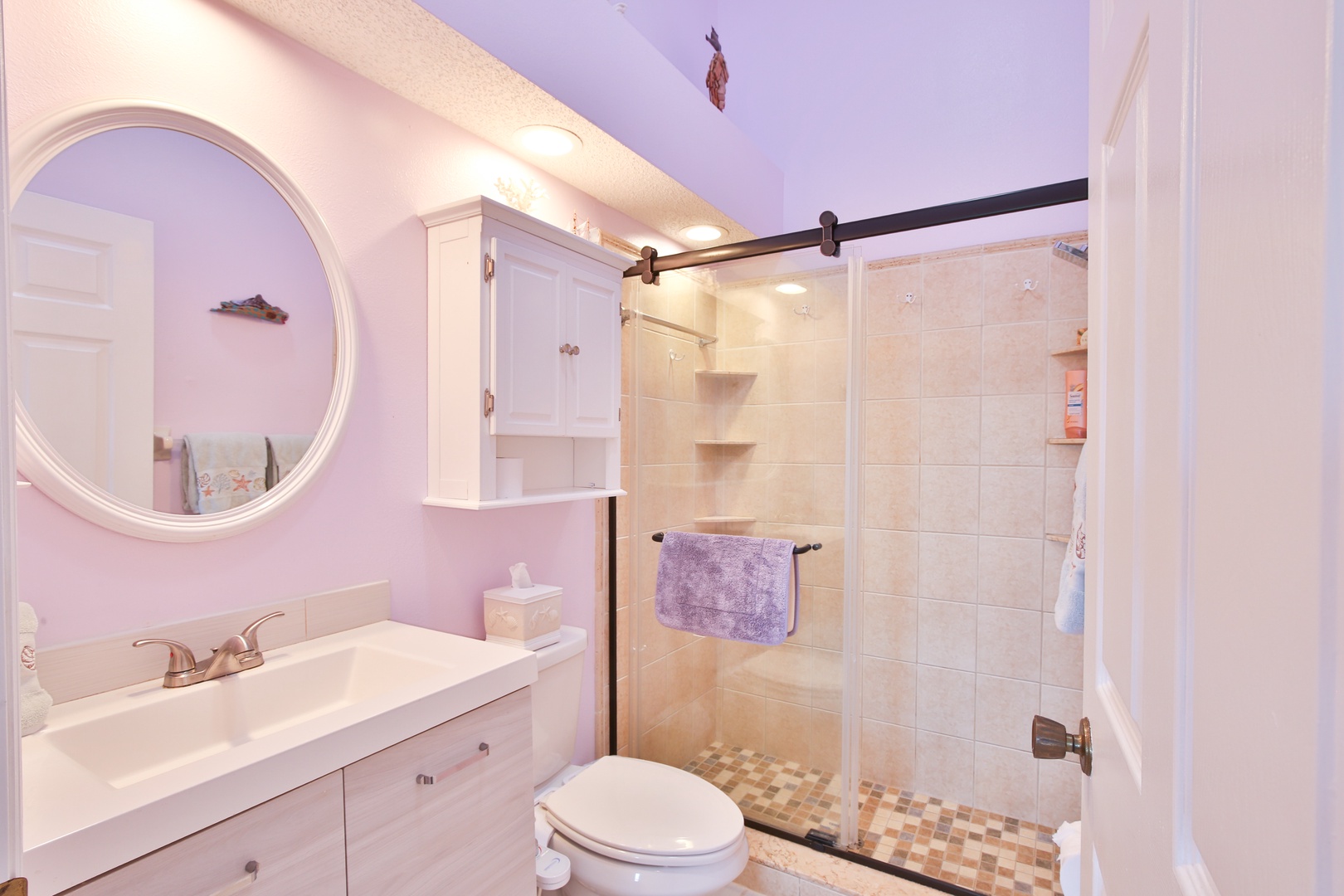 Refresh in your private bathroom with soft lavender walls, a spacious walk-in shower, and coastal-inspired decor that makes every moment feel like a retreat.