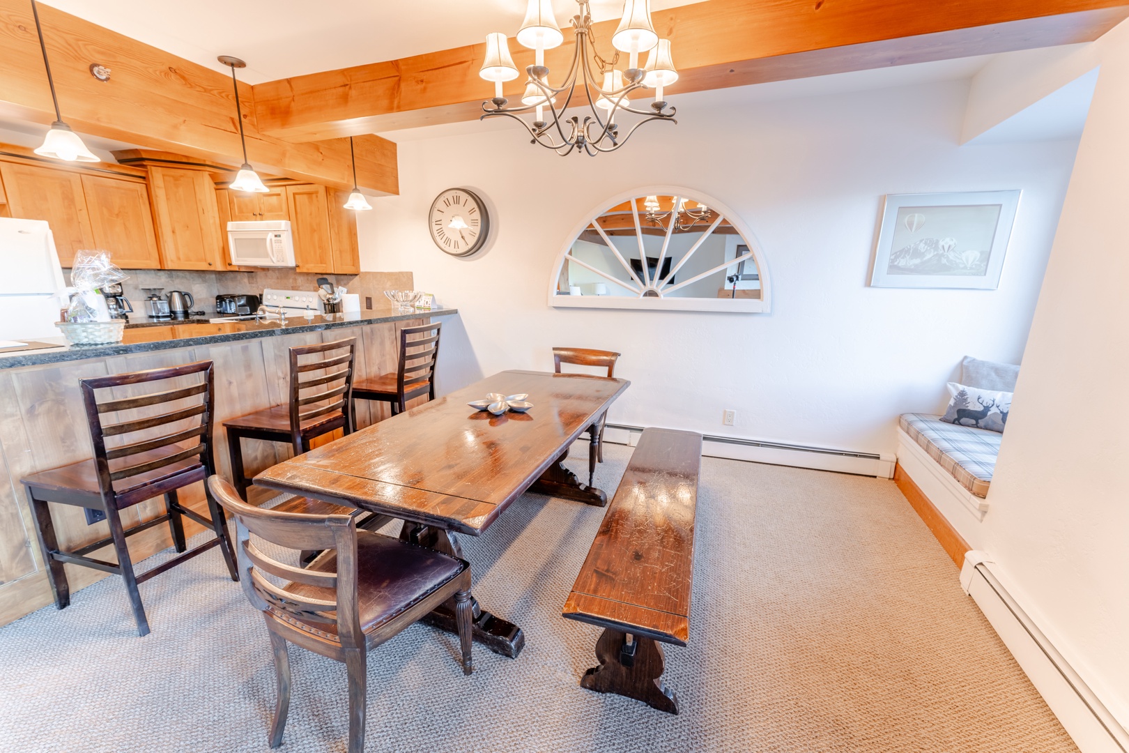 Gather around your warm wooden dining table while the chandelier casts a cozy glow over memorable meals shared together.