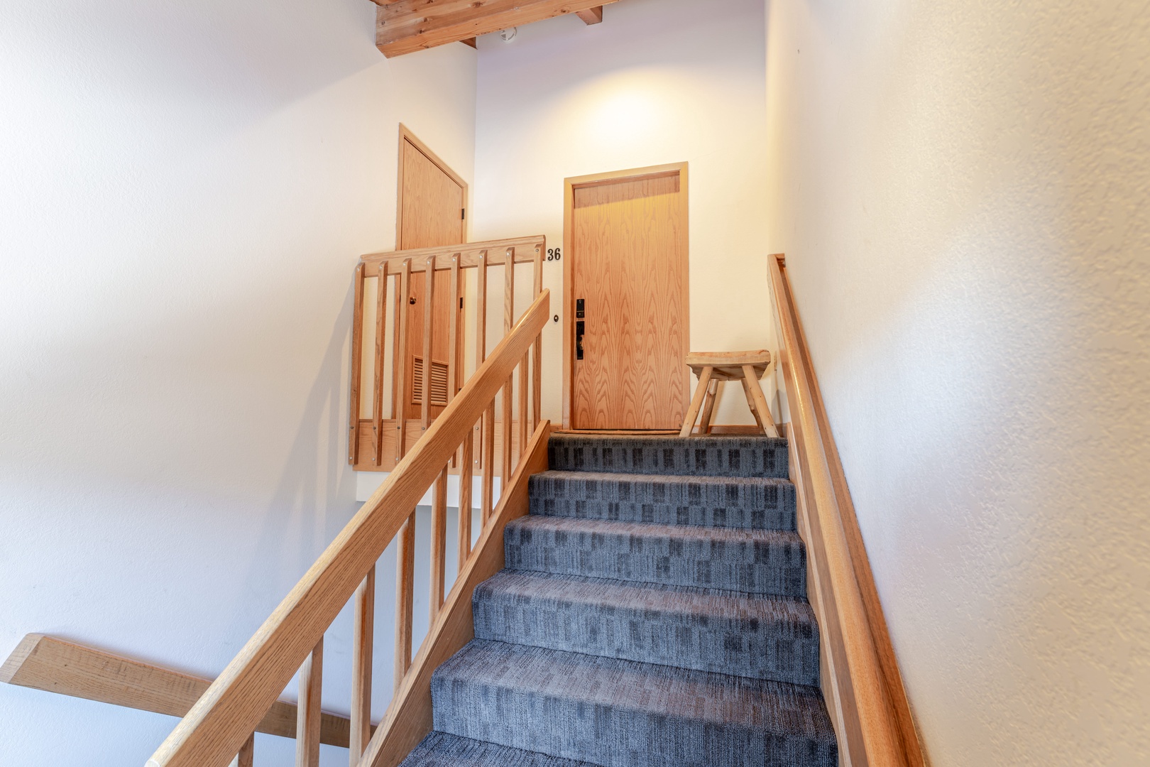 Climb the welcoming carpeted stairs to your cozy retreat, where warm wood details and exposed beams create an inviting mountain lodge atmosphere.