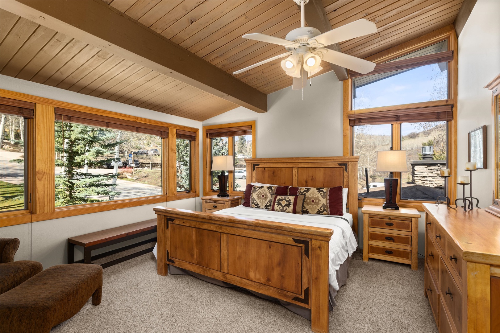 Wake up in your cozy bedroom with rustic wood beams overhead and mountain views through expansive windows.