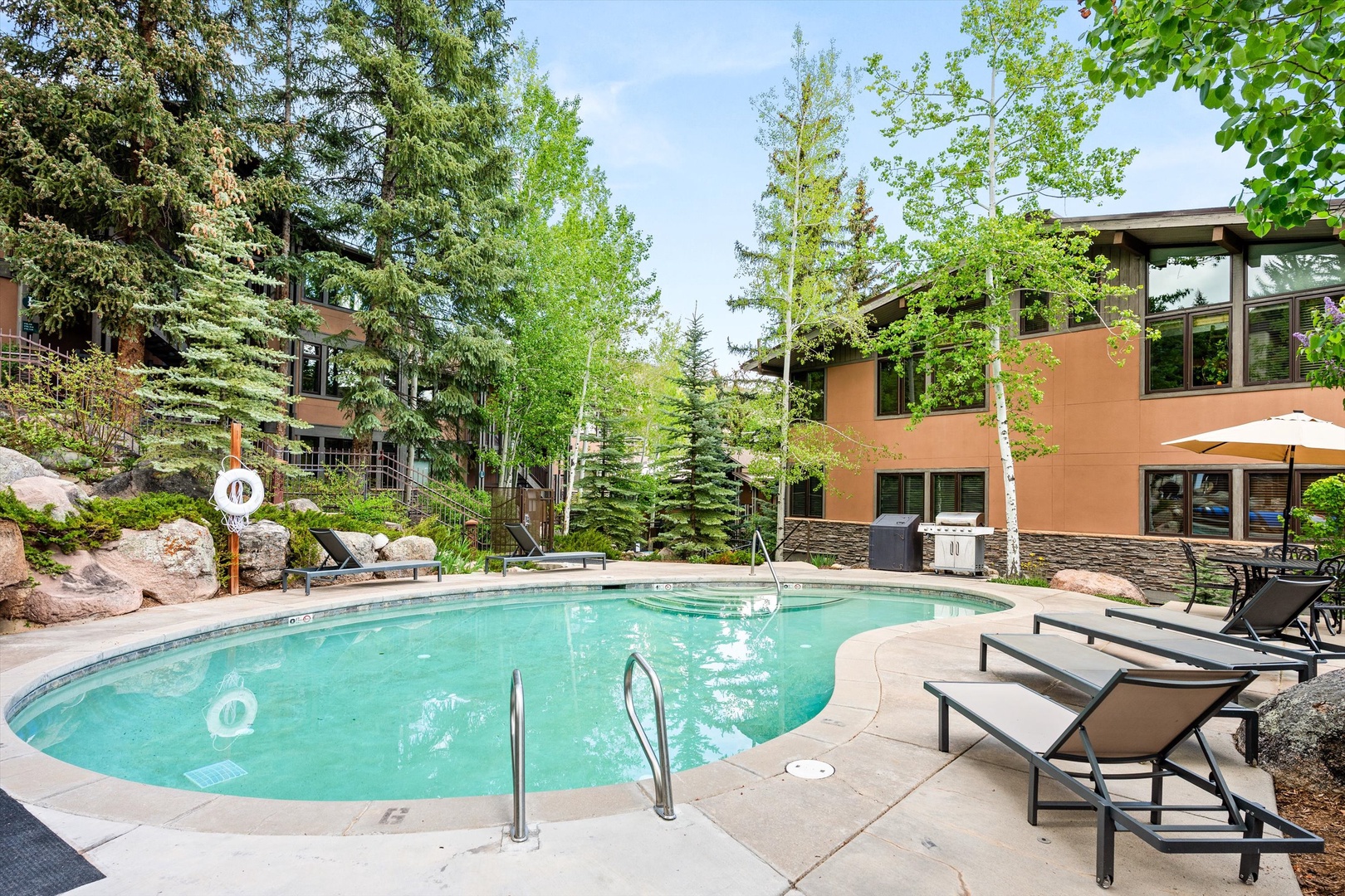 Soak up the sun beside this sparkling pool, surrounded by towering evergreens and modern architecture for the perfect retreat.