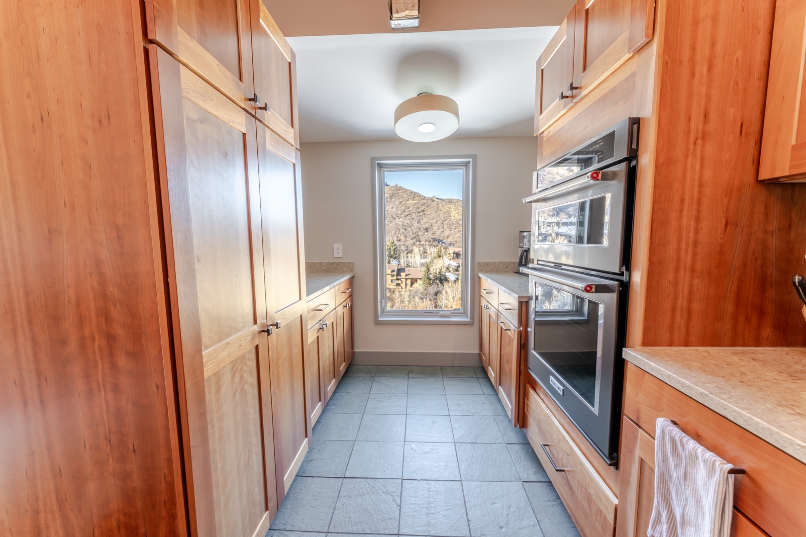 Your fully equipped galley kitchen features warm wood cabinetry and mountain views, perfect for preparing meals during your stay.