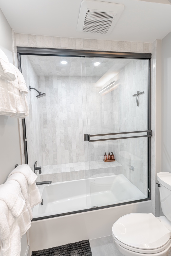 Unwind in your pristine guest bathroom featuring a luxurious tub-shower combo with marble-look tile and modern fixtures.