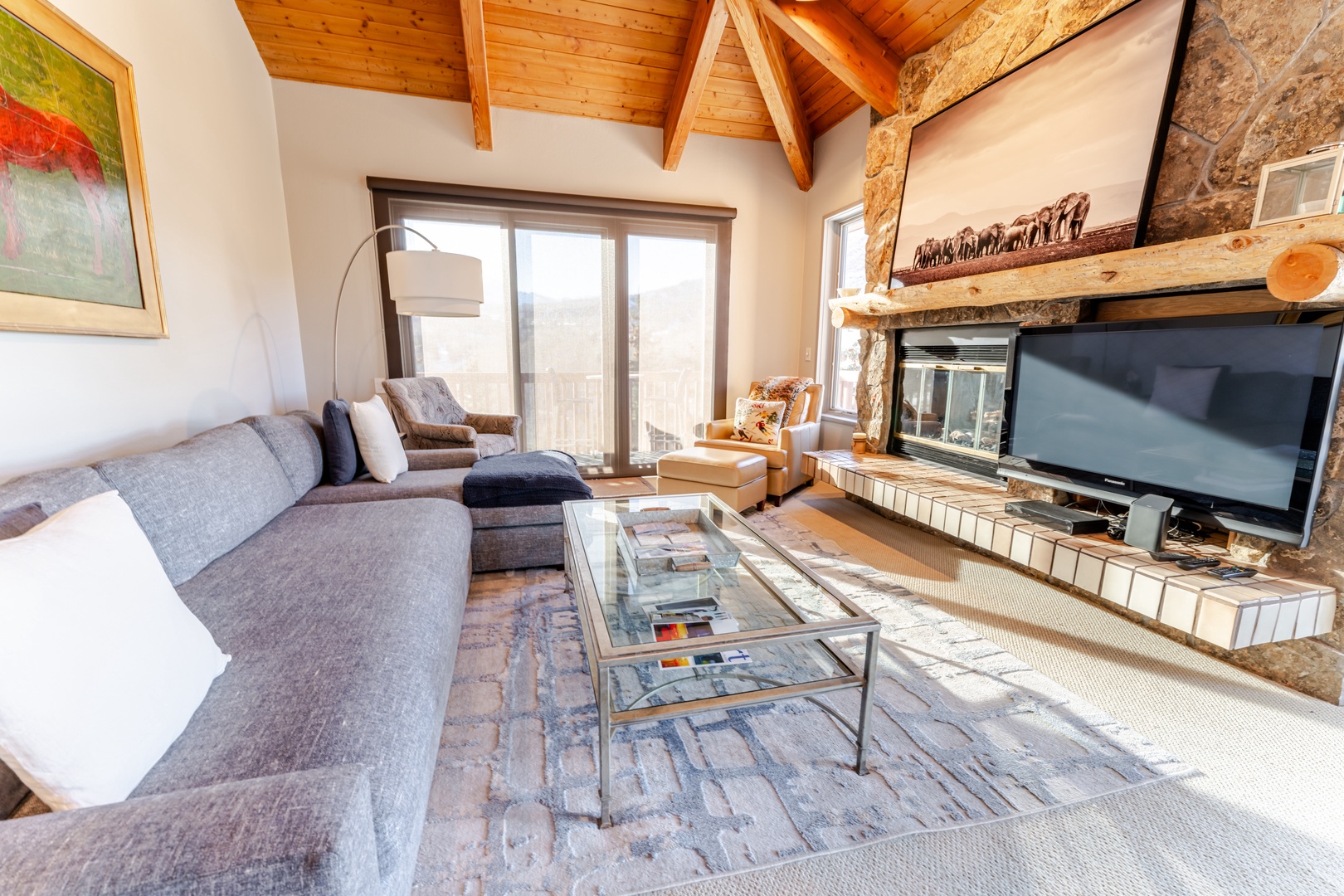 Unwind in your cozy living room with exposed beams, stone fireplace, and plush sectional sofa perfect for evening relaxation.