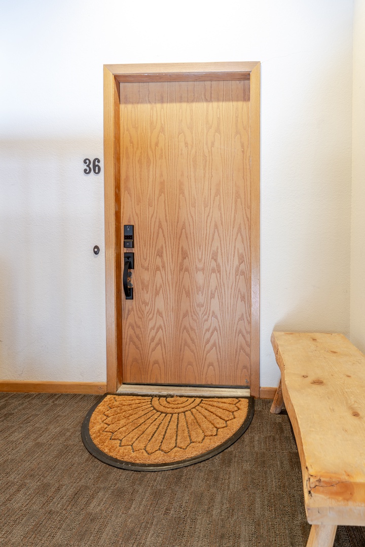 Step into room 36, where a welcoming doormat and warm wooden bench create your cozy home base.