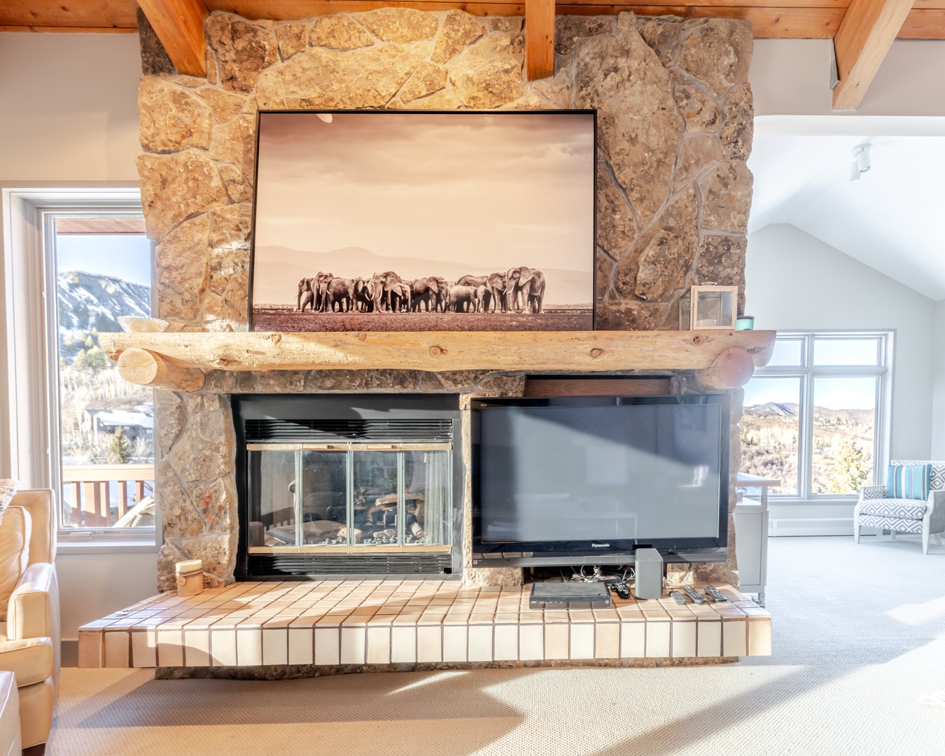 Cozy up by your stone fireplace with rustic wood beams overhead, where warm flames and mountain views create perfect evenings.