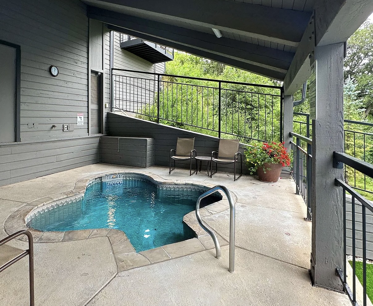 This covered terrace features a private hot tub with seating areas overlooking lush greenery—perfect for unwinding after a day of adventure.