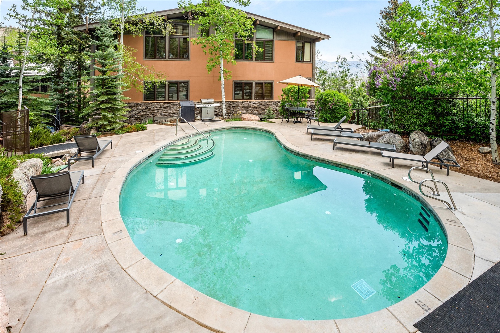 Dive into your private oasis with this sparkling pool surrounded by loungers, BBQ area, and lush landscaping for perfect relaxation.