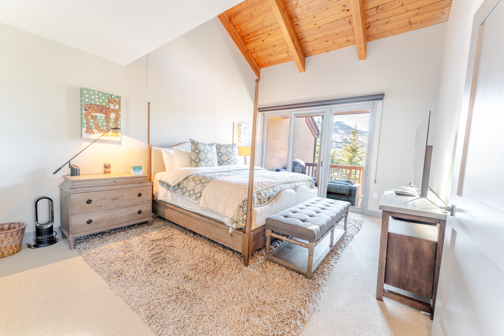 Rest peacefully in your elegant bedroom featuring exposed wood beams, a cozy four-poster bed, and private balcony access with stunning mountain views.