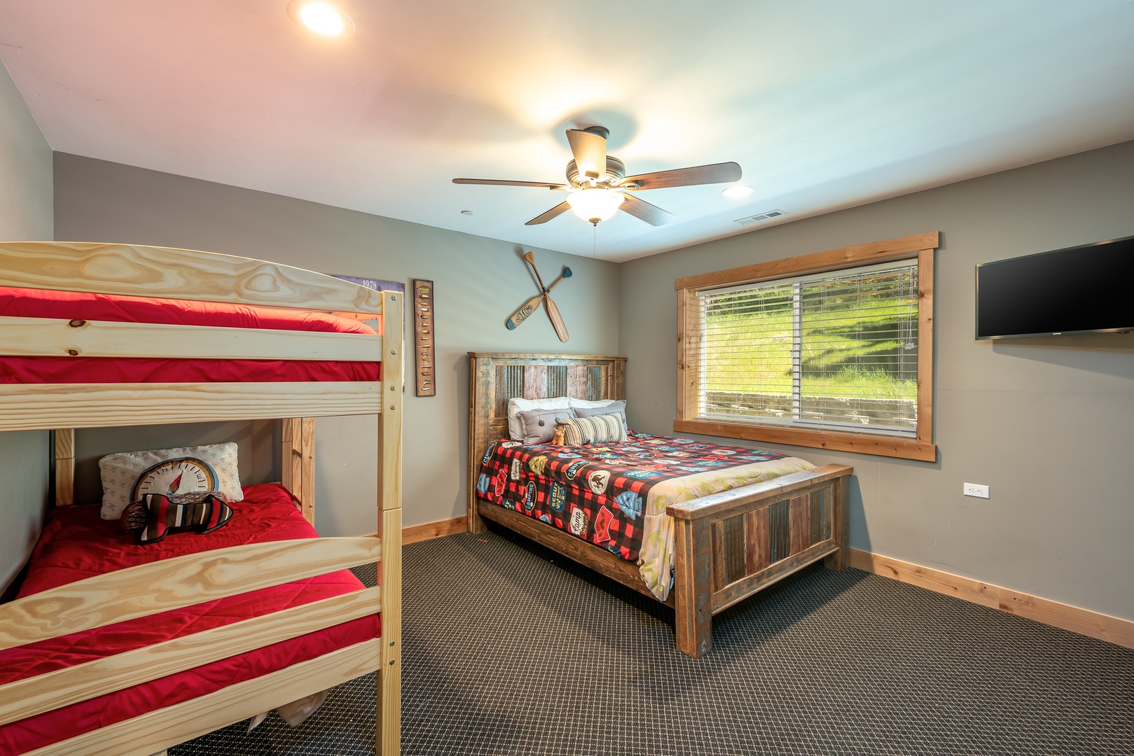 Rustic charm meets cozy comfort in this inviting bedroom, perfect for family stays. A sturdy bunk bed and a separate queen await guests for a night of slumber..