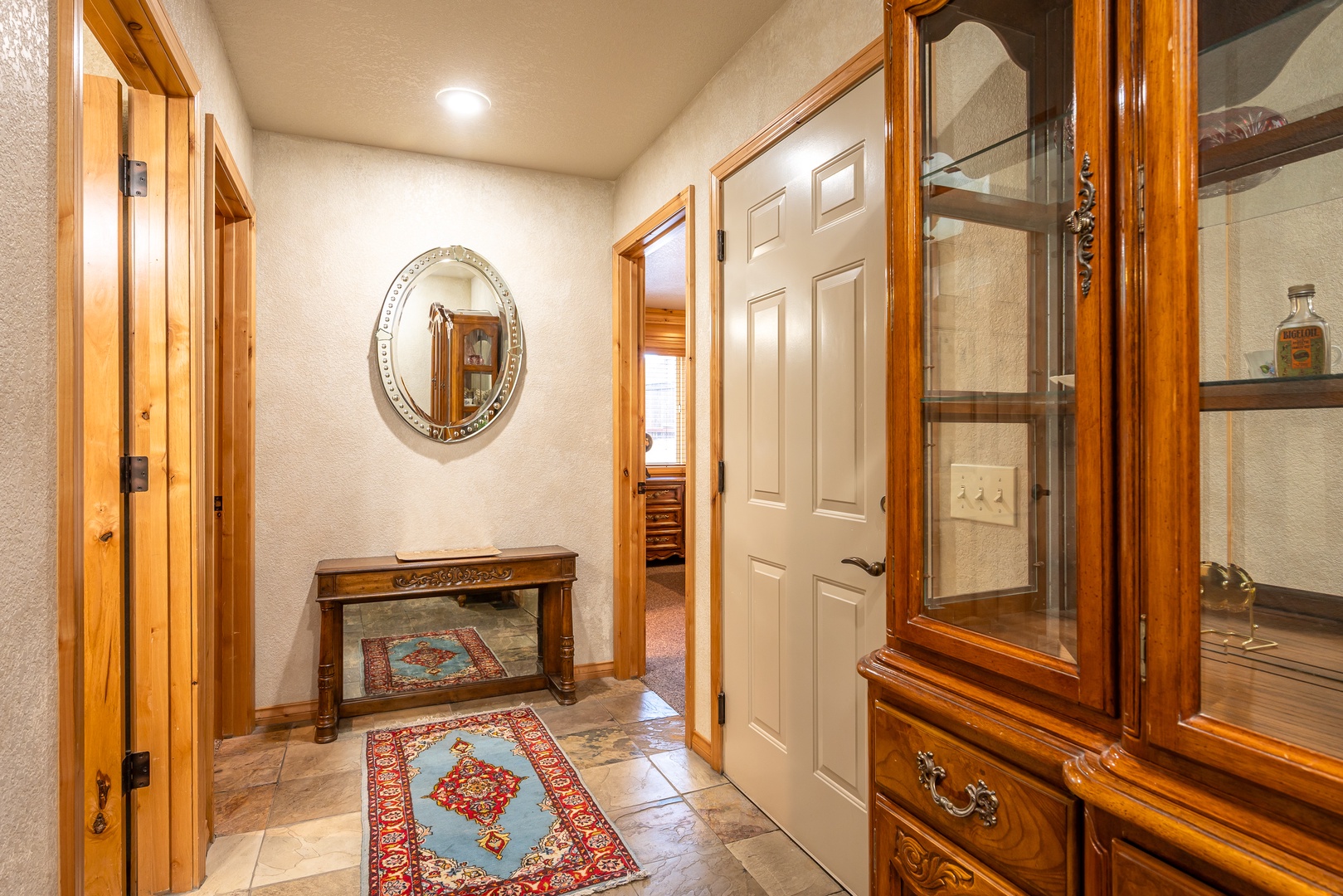 You'll feel welcomed the moment you step inside this warm hallway with rich wood accents, elegant furnishings, and beautiful Persian rugs.