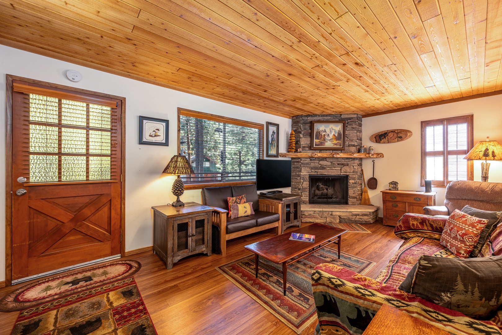 Unwind in your cozy living room with warm wood accents, a stone fireplace, and comfortable seating that invites you to relax after a day of adventure.