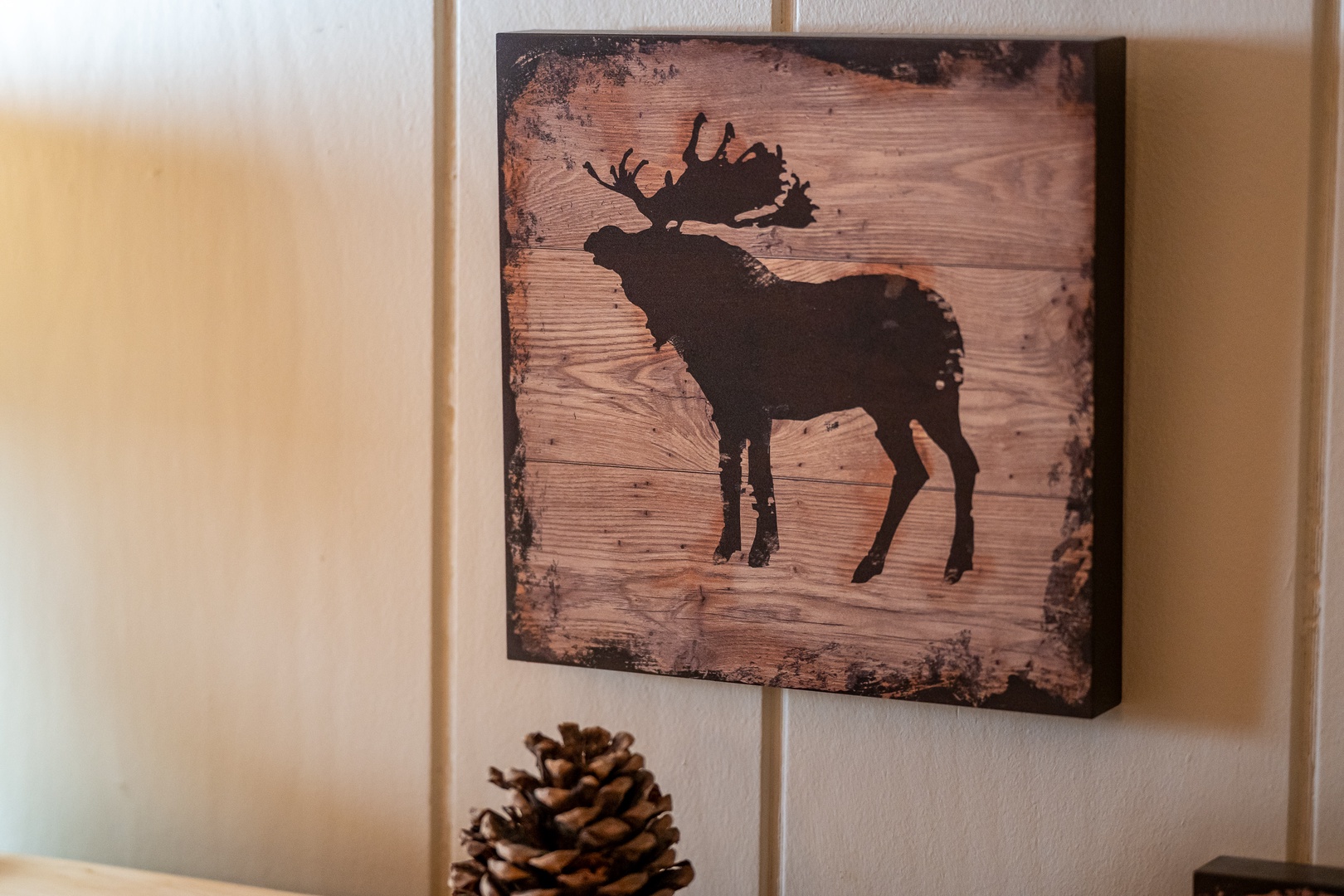 Rustic moose artwork and pinecones create a cozy woodland atmosphere in your mountain retreat.