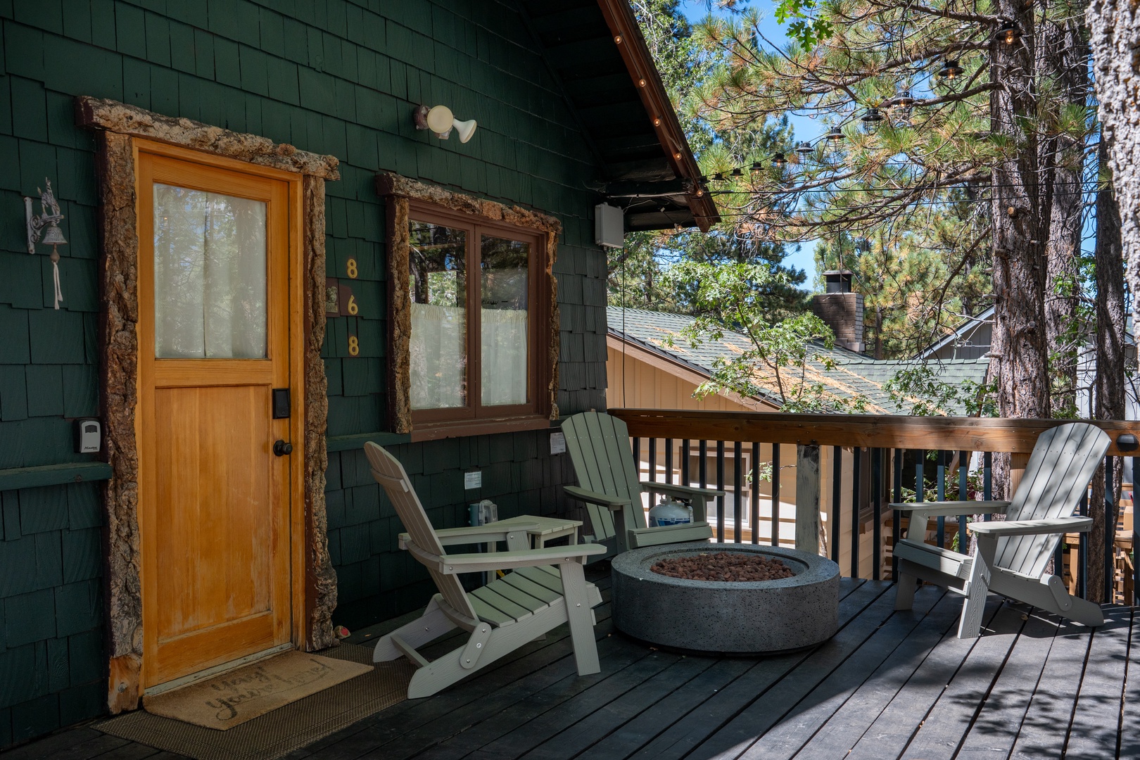 Rustic charm welcomes you to your mountain escape, where cozy Adirondack chairs circle a fire pit on your private deck. Tall pines frame the cabin's unique bark-trimmed entrance, inviting you into your peaceful wooded retreat.
