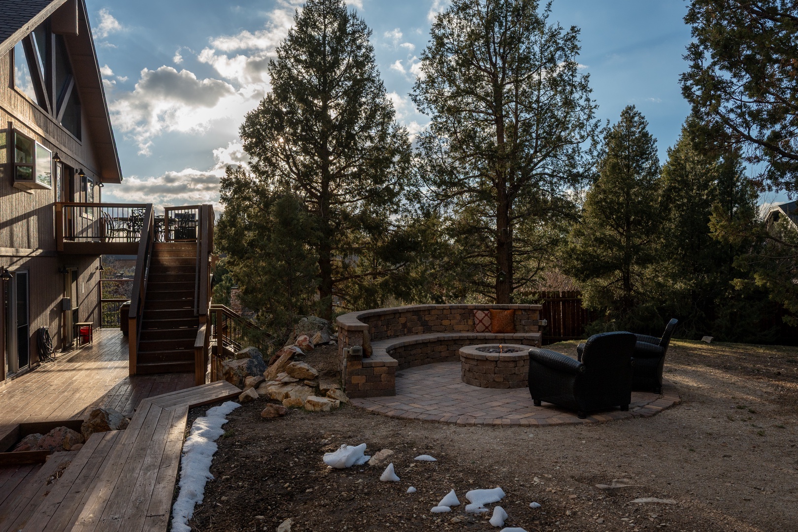 Beautiful outdoor fire pit area surrounded by mature trees and mountain views, perfect for evening gatherings.