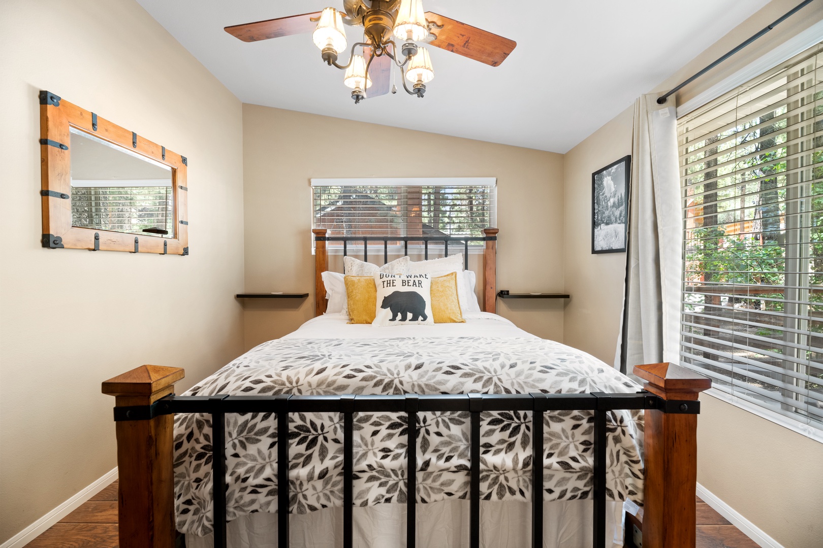 Sink into crisp linens beneath a gentle ceiling fan in your serene bedroom retreat, where rustic wood furnishings and natural light create a peaceful sanctuary for rest.