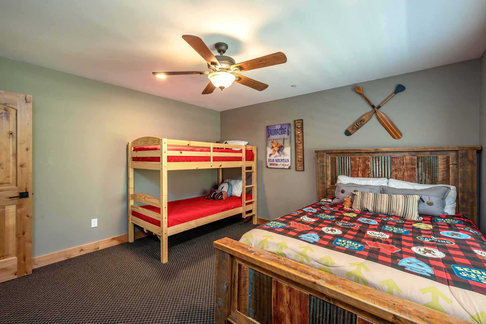 Rustic comfort meets playful charm in this spacious bedroom, featuring a cozy bunk bed and a beautifully handcrafted queen bed, perfect for families seeking mountain adventure.